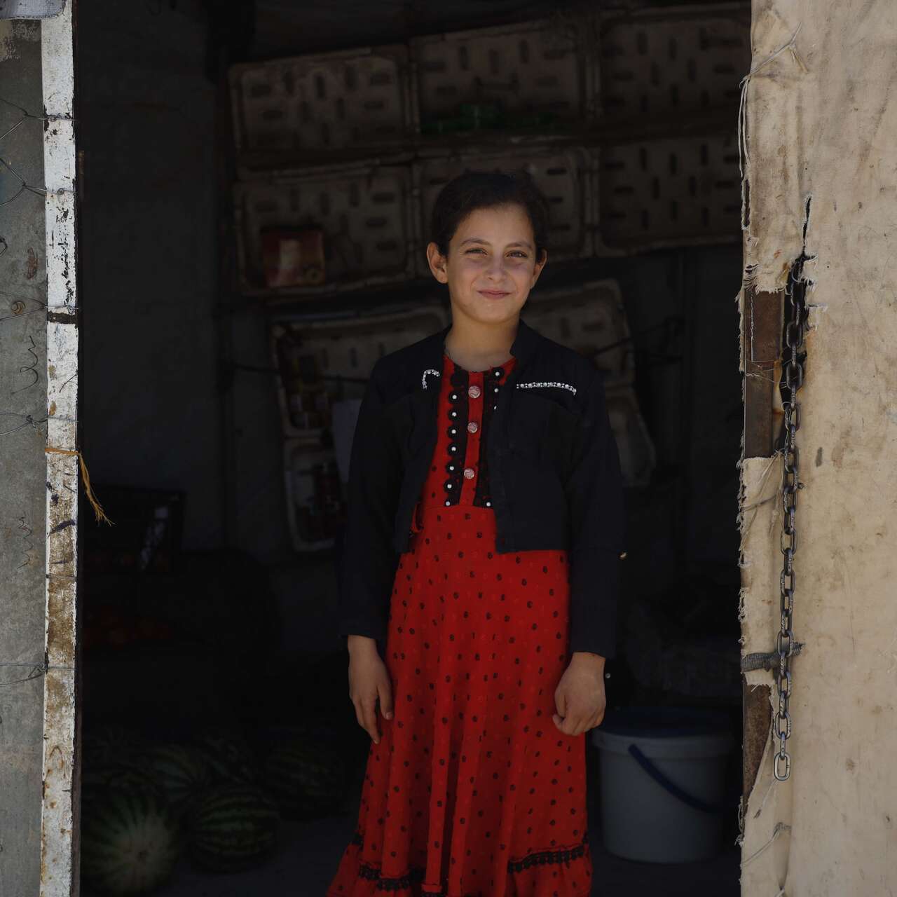 A girl stands in the middle of a doorway in Syria.